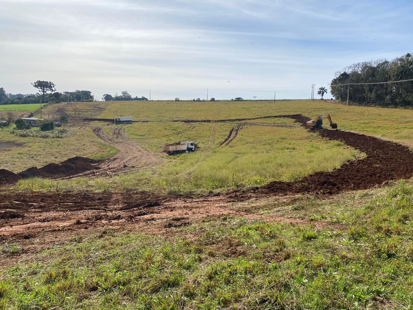 Área rural em processo de limpeza de terreno, com o material vegetal sendo retirado por caminhão